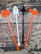 Set of Halloween-themed swizzle sticks on a wooden surface with decorative branches.